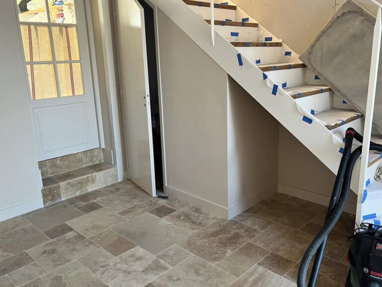 Rénovation d'entrée en Normandie avec peinture escalier blanc, marches bois et sol en carrelage pierre naturelle beige
